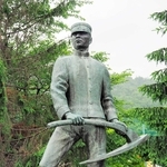 軍服にわらじをはいた姿で、くわを持つ屯田兵の像＝札幌市中央区