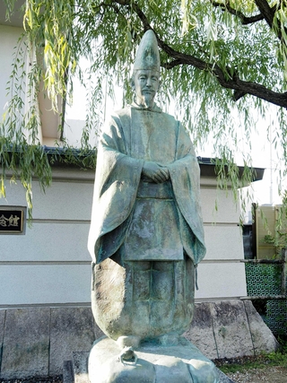 ヤナギの木の下に立つ小野道風の銅像。足元にはカエルも＝愛知県春日井市の道風記念館前