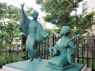 三味線をひき、おどりを教えているような永田いねの像（右）＝熊本市中央区