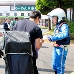 自転車利用者に注意をよびかけるチラシを配る警視庁の警察官＝東京都葛飾区