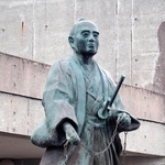 測量用のくさりを持って立つ間宮林蔵の銅像＝茨城県つくばみらい市の間宮林蔵記念館前