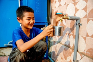 小学校で、雨水をろ過したきれいな水をコップに注ぐアンさん（日本ユニセフ協会提供）