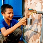 小学校で、雨水をろ過したきれいな水をコップに注ぐアンさん（日本ユニセフ協会提供）