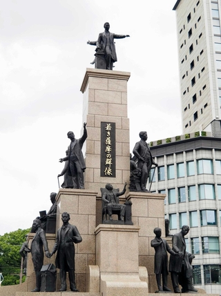 留学生ら１９人の銅像が並ぶ「若き薩摩の群像」。中央のいすにすわっている像が長沢鼎＝鹿児島市のＪＲ鹿児島中央駅前