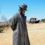 大正期の写真を再現した宮沢賢治の銅像。おくは賢治が住んだ家＝岩手県花巻市の県立花巻農業高校