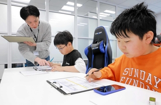 ゲームの品質管理を担当する池田さん（左）の説明を聞き、デバッグを体験する酒井悠太朗さん（中央）と松森優槻さん（（Ｃ）ＳＥＧＡ）
