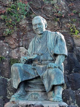 右手にせんすを持つ清水次郎長の銅像＝静岡市清水区の梅蔭禅寺
