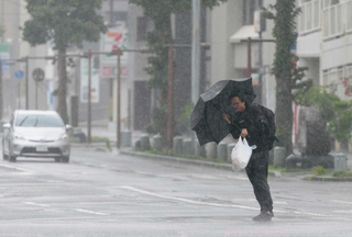 台風６号の影響で風雨が強まる中、歩く男性＝６月２日、鹿児島市