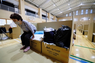 ７月に発生した熊本地震で、避難所に組み立てられた段ボール製のベッドにこしかける女性。「足をのばして寝られ、本当に快適です」＝熊本県宇城市