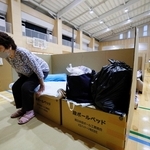 ７月に発生した熊本地震で、避難所に組み立てられた段ボール製のベッドにこしかける女性。「足をのばして寝られ、本当に快適です」＝熊本県宇城市