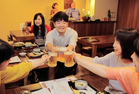 夜の商店街を楽しむ大人向けツアー「水道筋的裏ミシュラン」。参加者と乾杯する末吉佳希記者＝灘区水道筋２、うどん店「な也」
