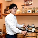 本社１階に設けられた直売店で、コーヒー豆をすくう萩原英治さん＝灘区城内通１