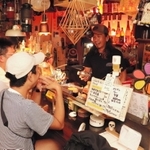 キャンプ道具の説明をお客さんにする殿本真一さん＝焼き鳥店「チンタ」