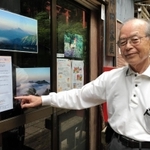 高取山の中腹にある茶屋に掲示した「心のポスト」のちらしを案内する小西清次さん＝長田区高取山町