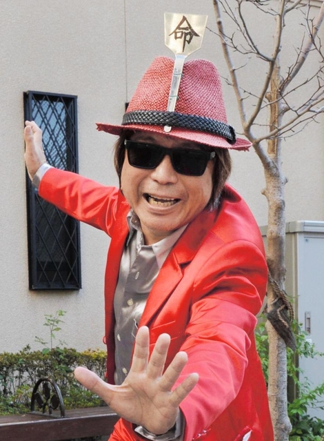 赤いスーツにコテが付いた帽子をかぶり、ポーズをとる「鉄板コテ之介」こと上野栄一さん＝神戸市長田区水笠通４