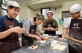 パンの仕込みをする石倉さん（左から３人目）とメンバーら。笑みもこぼれる＝くららべーかりー