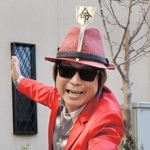 赤いスーツにコテが付いた帽子をかぶり、ポーズをとる「鉄板コテ之介」こと上野栄一さん＝神戸市長田区水笠通４