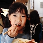 「長い列を待って良かった」とお好み焼きを頰張る宗和明花音ちゃん＝神戸市長田区腕塚町２