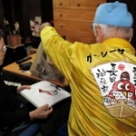 利用者に商品を手渡す萬福グージーサービス宅配の配達員（右）＝神戸市長田区内