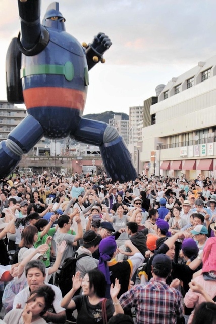 １０月の琉球祭で、鉄人２８号の実物大モニュメントの前で踊る参加者ら＝若松公園