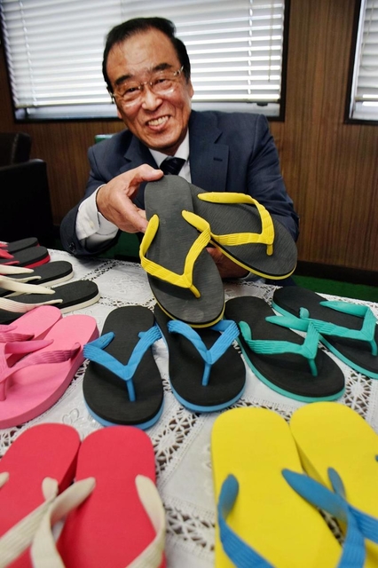 世界初のビーチサンダルを手にする内外ゴムＯＢ会会長の相川征四郎＝明石市