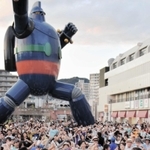 １０月の琉球祭で、鉄人２８号の実物大モニュメントの前で踊る参加者ら＝若松公園