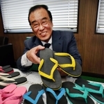 世界初のビーチサンダルを手にする内外ゴムＯＢ会会長の相川征四郎＝明石市