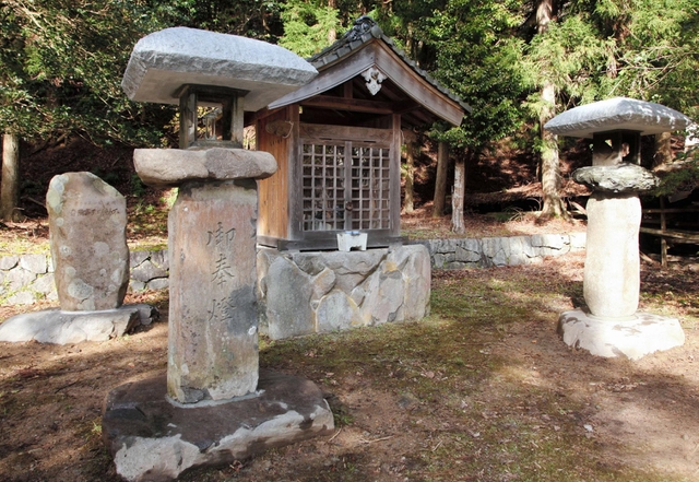 鉱山の麓に移設された石灯籠（手前）と石碑（左奥）笠石は御影石で新調された＝朝来市佐囊