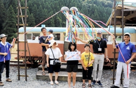 「一円電車体験乗車会」の３万人目の利用者となった明石市の村井凜さん（中央）や家族ら＝養父市大屋町明延