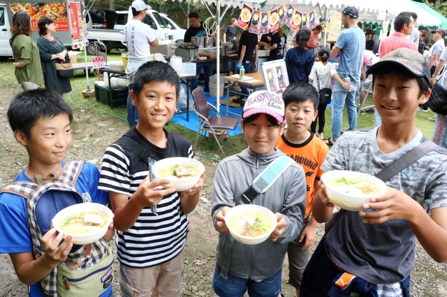 人気店のラーメンを手にして笑顔を見せる子どもたち＝生野銀山駐車場
