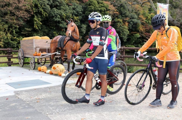 馬車のモニュメント付近で自転車を降りて休憩する参加者＝神河町吉冨