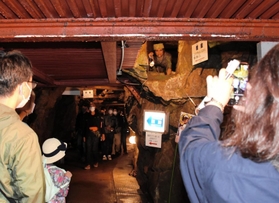 坑道などを回り、銀山ボーイズの説明やエピソードを聞くツアー参加者たち＝史跡・生野銀山