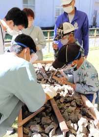 鉱山から採掘された鉱石を割ってキラキラとした金属を確かめる子どもたち＝養父市大屋町明延