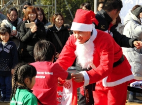 サンタクロース姿でサインが入ったマインツのユニホームをスクール生に贈る岡崎慎司＝２０１４年１２月２３日、神戸市西区の滝川第二高