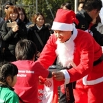 サンタクロース姿でサインが入ったマインツのユニホームをスクール生に贈る岡崎慎司＝２０１４年１２月２３日、神戸市西区の滝川第二高