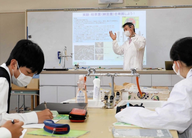 ため池の水質改善に向け、滝川第二高校の化学同好会を指導する三重大学の田丸浩教授（奥）＝神戸市西区春日台６