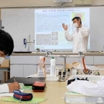ため池の水質改善に向け、滝川第二高校の化学同好会を指導する三重大学の田丸浩教授（奥）＝神戸市西区春日台６