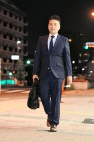 本業ではスーツ姿の酒井英徳さん＝芦屋市川西町（撮影・中西幸大）