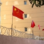 新疆ウイグル自治区・カシュガルの有刺鉄線の壁にある中国の旗（Jonathan Densford/stock.adobe.com）