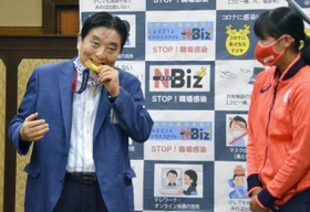 後藤希友投手（右）の金メダルを噛む河村たかし市長＝４日（提供・共同通信社）