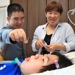 筋ジストロフィーのお姉ちゃんにラムネのお菓子を上げるコウタ（左）と母のヒロミさん。あーん！と楽しい掛け声で＝神戸市内