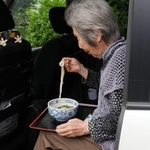 後部座席でうどんを食べるおばあちゃん　※再現写真（松浦産業提供）