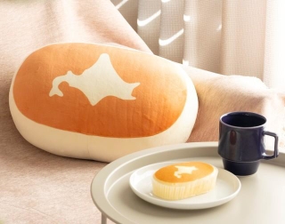 「北海道チーズ蒸しケーキ」そっくり！ビッグなぬいぐるみ（写真奥）（宝島社提供）