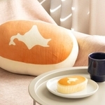 「北海道チーズ蒸しケーキ」そっくり！ビッグなぬいぐるみ（写真奥）（宝島社提供）