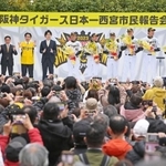 壇上で日本一を報告する阪神タイガースの選手らに向かって六甲おろしを合唱するファンたち