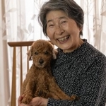 愛犬のトイプードルを笑顔で抱きかかえる高齢者女性（ururu/stock.adobe.com）