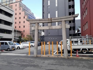 都会の道路にポツンと鳥居だけが建っている