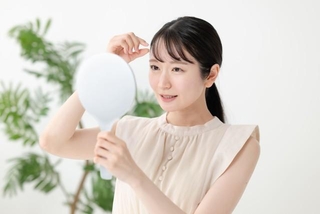 前髪をチェックする女性　※写真はイメージ（Peak River/stock.adobe.com）
