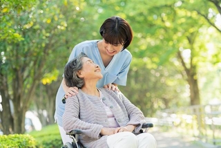 車いすに乗る女性と笑顔で話す看護師※画像はイメージです（One/stock.adobe.com）