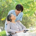 車いすに乗る女性と笑顔で話す看護師※画像はイメージです（One/stock.adobe.com）